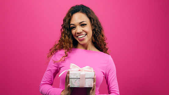 Beautiful young woman poses with gift box pink studio, Valentines or anniversary. High quality photo