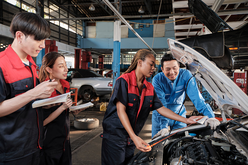 Male professional automotive supervisor advises and inspects Black female mechanic worker about liquid engine oil at car garage, service maintenance, and fixing specialist occupations auto industry.