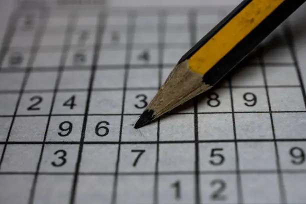 Photo of Sudoku puzzle grid and pencil, closeup view