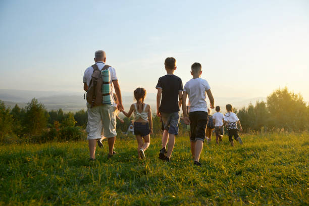 istock Old man leading kids forward in hills. 1783679833
