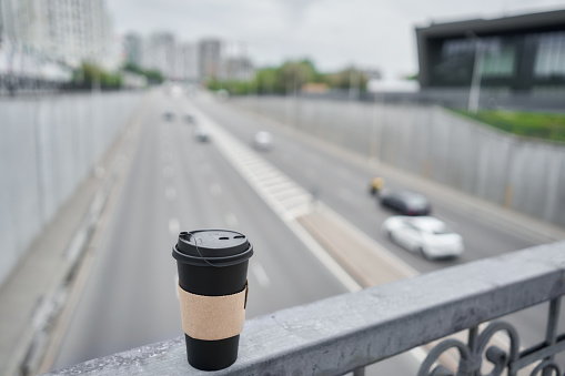 A cup of hot drink . A man on the city highway holds a cup of coffee in her hands. Breakfast on the go. The concept of a picnic and going out.