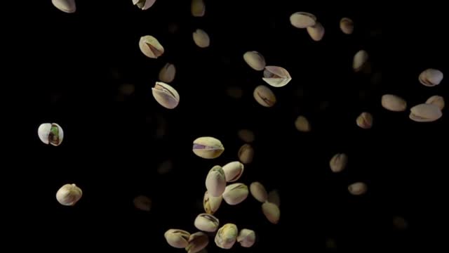 Top view of salted pistachios flying up on a black background