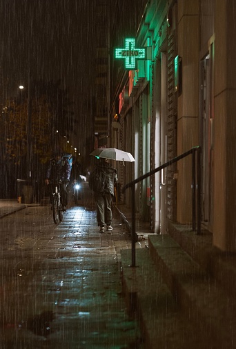 Warsaw, Poland – November 03, 2023: A group of people are seen walking down a wet and slick sidewalk during a rain shower.