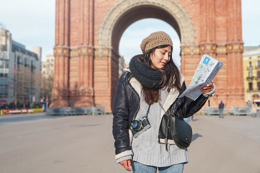 Asian Japanese woman tourist woman sightseeing Barcelona holding city map in winter vacations
