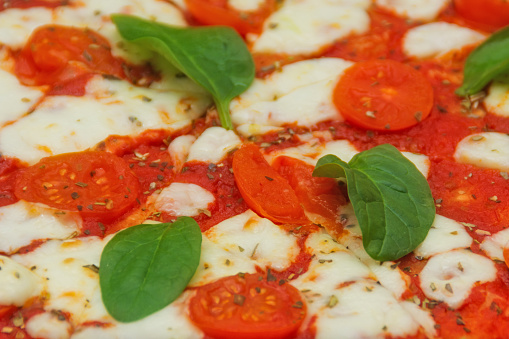 Traditional Margherita pizza with fresh tomatoes and spinach leaves