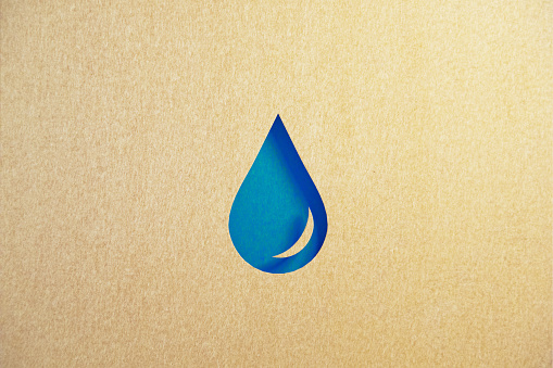 Cut out water droplet shape made of recycled paper on blue background. Horizontal composition with copy space. Sustainability and clean water concept.