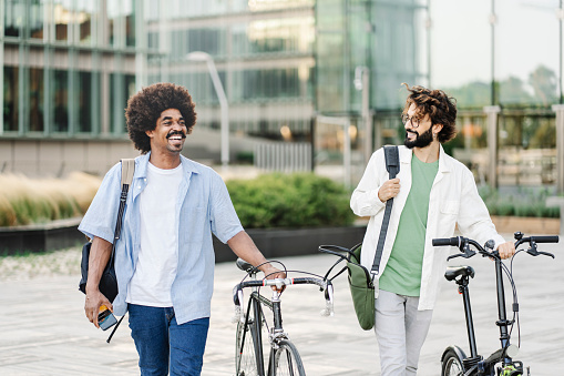 Two young male friends with bicycle - Modern coworkers walking outside office