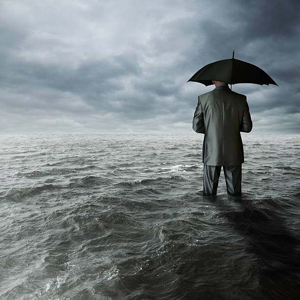 istock Man in suit holding an umbrella standing in churning surf 178368955