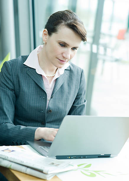 Checking e-mail Business woman working on notebook newspaper airport reading business person stock pictures, royalty-free photos & images