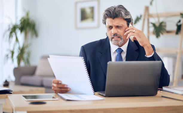 istock Document, laptop and businessman on a phone call in the office while talking to a client. Discussion, technology and mature professional male lawyer on mobile conversation with paperwork and computer 1783693679