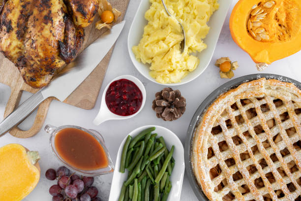 istock Thanksgiving day dinner table with roasted chicken or turkey, apple pie and other holiday season foods. Traditional autumn fall feast flat lay composition. 1783694309