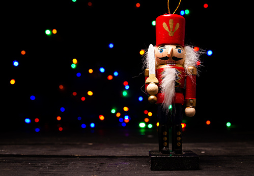 Traditional Christmas nutcracker wooden figure. Beautiful, festive toy soldier decoration, with copy space and tree lights bokeh in background.