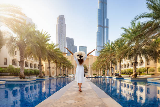 A tourist woman in a white summer dress walks through the streets of Dubai A happy tourist woman in a white summer dress walks through the streets of Dubai, UAE, during her holiday time dubai street stock pictures, royalty-free photos & images