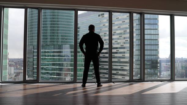 istock A man in a suit in the office opposite a panoramic window. A confident man approaches the window against the backdrop of skyscrapers. 1783700904