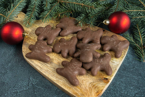 istock Chocolate gingerbread man cookies, Christmas tree branches and red baubles ornaments decorations. 1783704571
