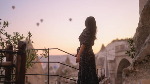 ritratto di giovane turista che guarda i balloni ad aria calda dal balcone in cappadocia durante il suo viaggio - traditional festival adventure air air vehicle foto e immagini stock
