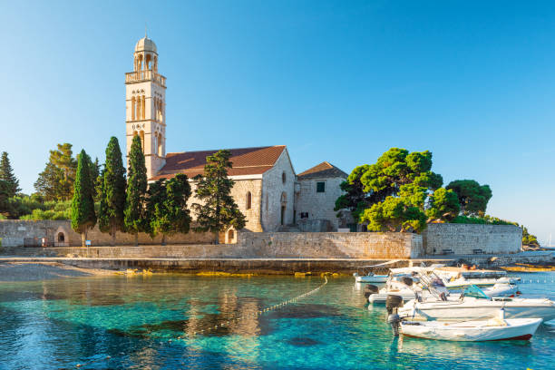 agua turquesa de la bahía del mar adriático en la isla de hvar con monasterio francisciense y barcos en la región de dalmacia, croacia al amanecer - morning croatia blue sea fotografías e imágenes de stock