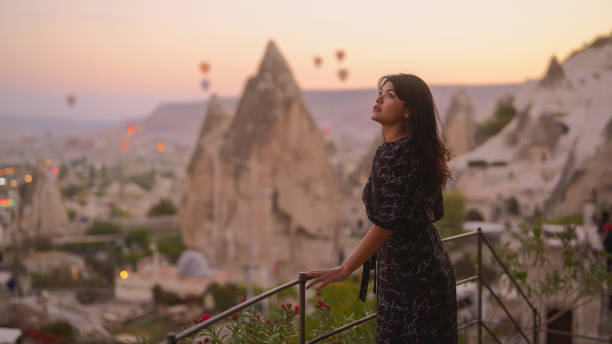 ritratto di giovane turista che guarda i balloni ad aria calda dal balcone in cappadocia durante il suo viaggio - traditional festival adventure air air vehicle foto e immagini stock