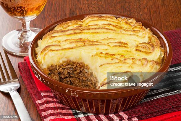 Cottage Pie In A Brown Dish Next To A Fork And Glass Of Wine Stock Photo - Download Image Now