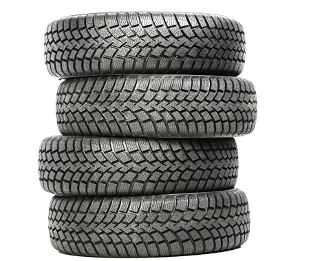 Stack of four wheel new black tyres for winter car driving isolated on white background