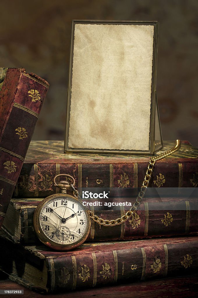 Frame with old photo paper texture, pocket watch and books Vintage wood desk with Antique Frame with old photo paper texture, Books and Old Pocket Clock in Low-key. Pocket Watch Stock Photo