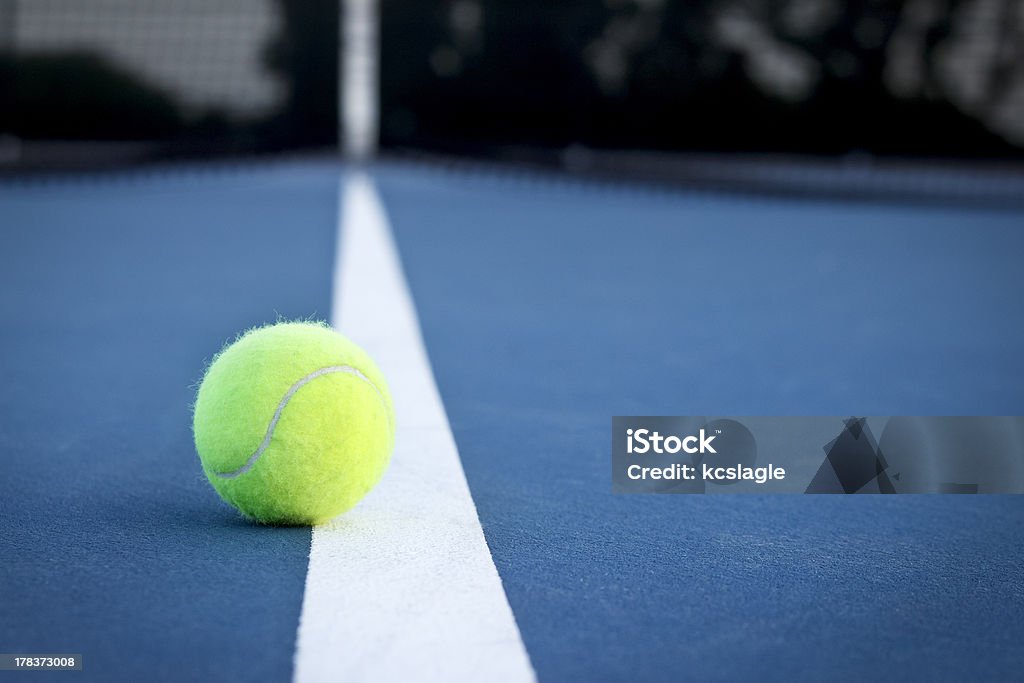 Tennis Ball on the Line A tennis ball on the line at dusk. Tennis Stock Photo
