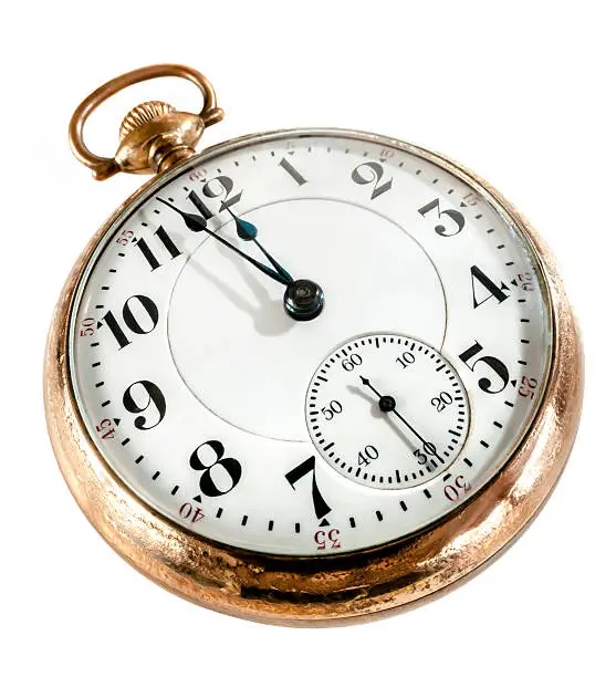 Antique golden pocket watch showing a few minutes to midnight isolated.