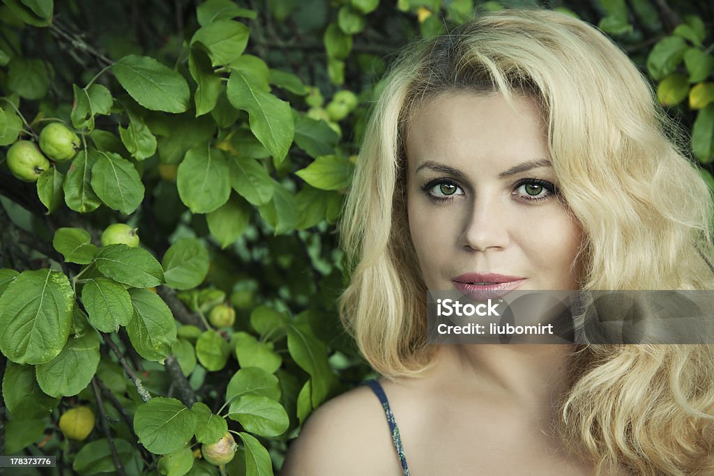 Eve and forbidden fruits portrait of a beautiful blonde woman next to apple tree with selective focus Adult Stock Photo