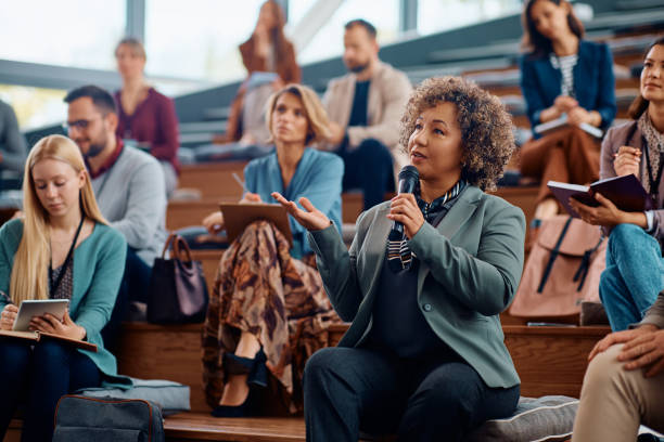 istock Mature businesswoman using microphone while speaking from audience during a seminar. 1783738725
