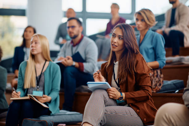 istock Young businesswoman writing in notebook while participating in  education event at convention center. 1783739283