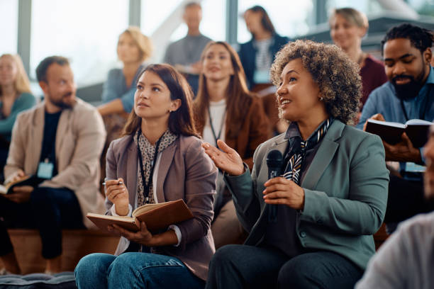 istock Female manager asking a question from the audience while participating in business seminar at convention center. 1783743109