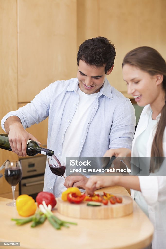 Mignon homme verser le vin, tandis que sa femme est la cuisine - Photo de 20-24 ans libre de droits