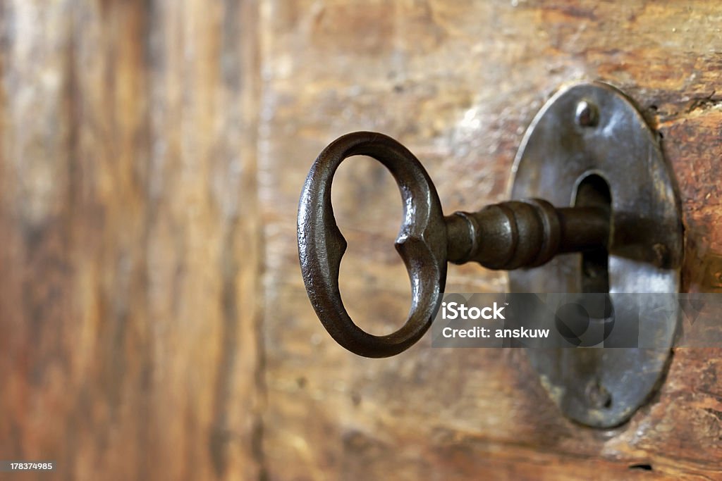 Closeup of an old keyhole with key Closeup of an old keyhole with key on a wooden antique door Key Stock Photo