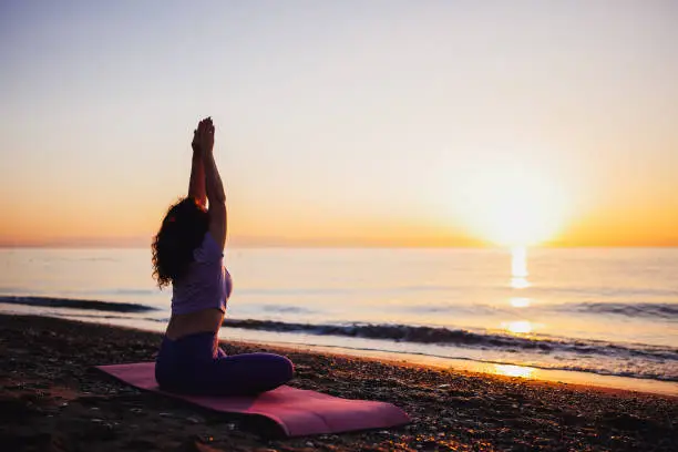 Photo of Carefree woman yoga practicing by the sea sunrise time