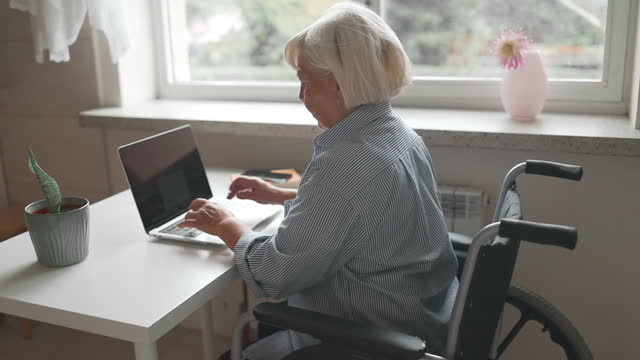 Close-up of woman wheelchair user typing on laptop, working from home, freelance