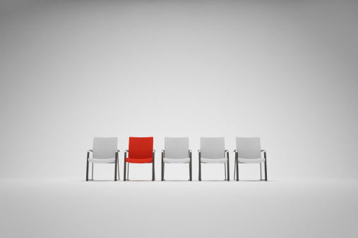 Red chair in a row of white ones
