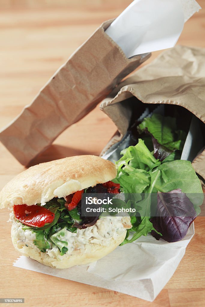Chicken salad sandwich and brown paper bags Chicken salad sandwich on white parchment paper garnished with leafy green mix alongside brown paper bags. Bell Pepper Stock Photo