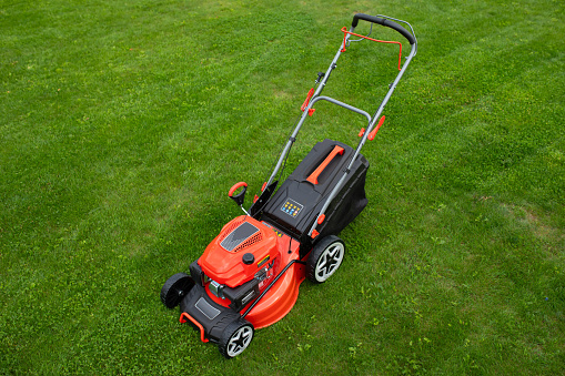 petrol self-propelled lawn mower on green grass.