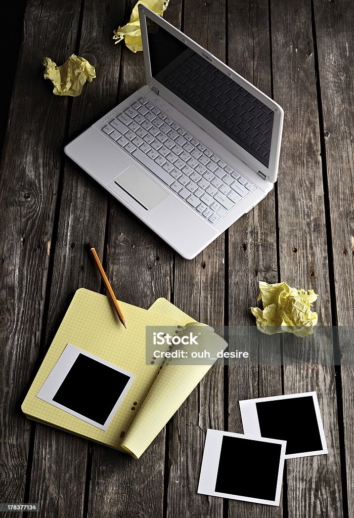 Laptop, instant photos and crumpled paper on table. Laptop with blank instant photos and notepad with sheets of crumpled paper on old wooden table. Workplace writer. Internet Stock Photo