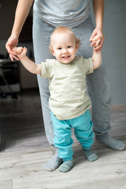 istock happy little baby learning to walk with mother help at home 1783780055