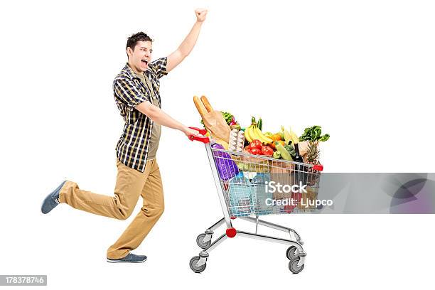 Foto de Feliz Homem Empurrando Um Carrinho De Compras e mais fotos de stock de Carrinho de compras - Carrinho de compras, Supermercado, Cheio