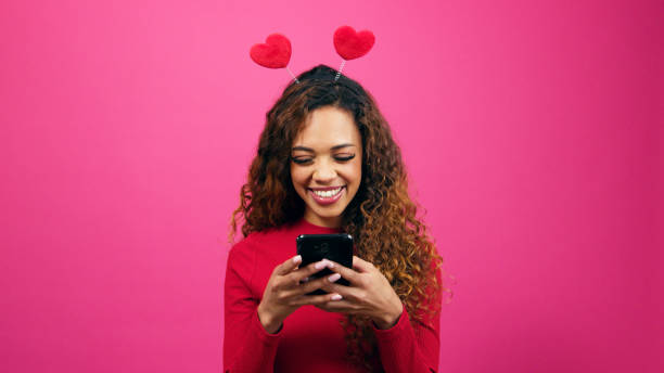 istock Cute young woman dressed for Valentines Day on dating app cellphone, studio 1783797297