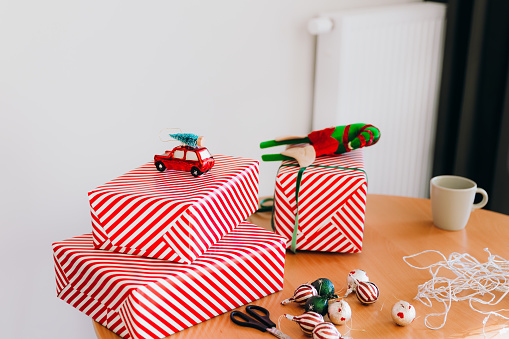 Group of red wrapped boxes with Christmas toys candies and Christmas Lights on the table in modern bright living room