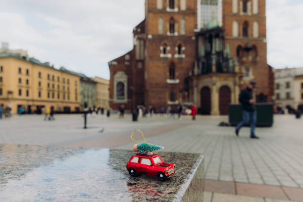Small Christmas Tree toy - a red vintage car with green Christmas tree on the roof on the streets of old town of Krakow