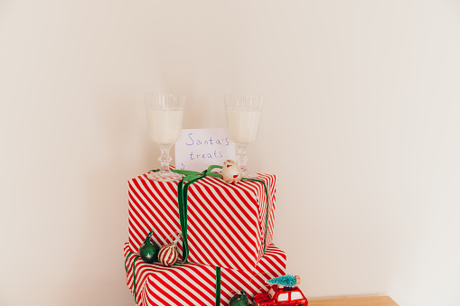 Group of red wrapped boxes with Christmas presents, Christmas toy red car with tree on the roof and two glass on milk above it with a greeting card 