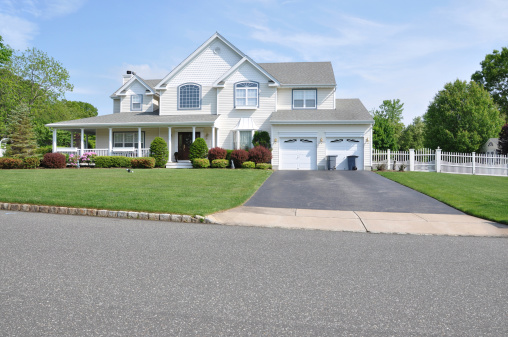 Two story double car garage with trash can containers landscaped front yard beautiful large suburban home
