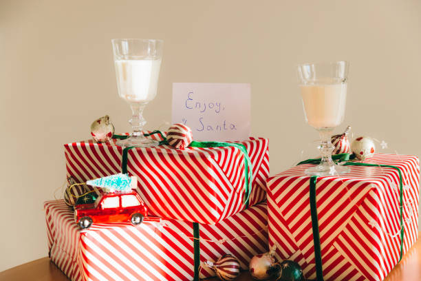 Group of red wrapped boxes with Christmas presents, Christmas toy red car with tree on the roof and two glass on milk above it with a greeting card \