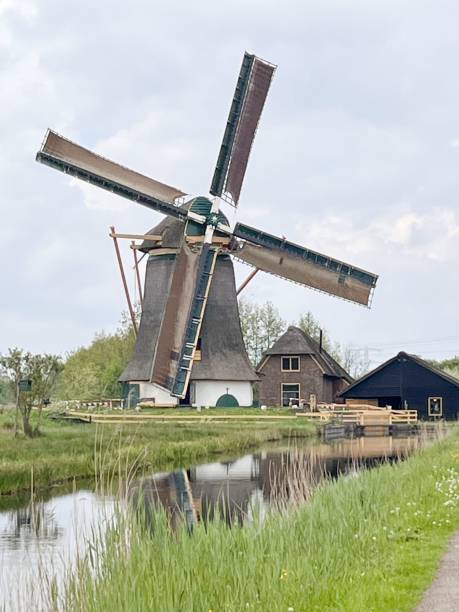 istock an old windmill sits next to the water with boats in it 1783810972