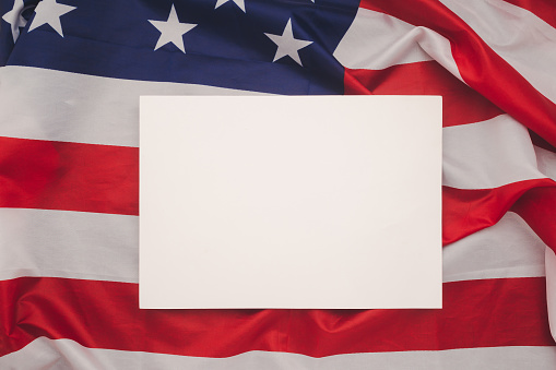 A blank white paper over the American flag. Space for text. Advertisement concept