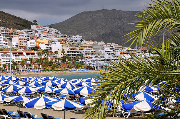 Umbrellas on the beach and town of Los Cristianos of the southern part of Tenerife in the Spanish Canary Islands